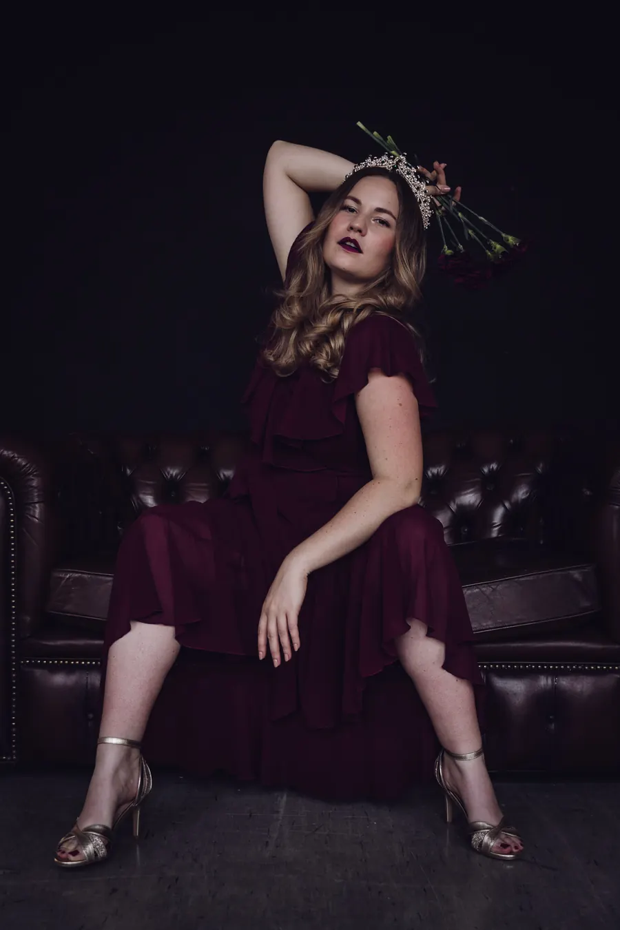 Corinna Kehl mit Krone auf einem dunklen Chesterfield-Sofa